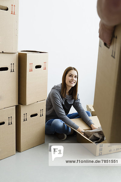 Young man holding cardboard box while woman packing box