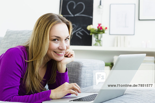 Portrait einer jungen Frau am Laptop  lächelnd