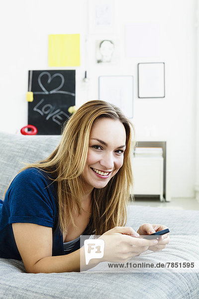 Portrait of young woman holding mobile phone  smiling