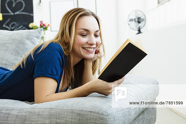 Junge Frau liest Buch  lächelnd