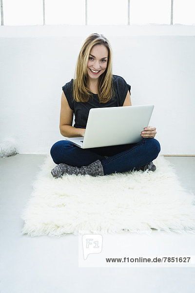 Portrait einer jungen Frau am Laptop  lächelnd