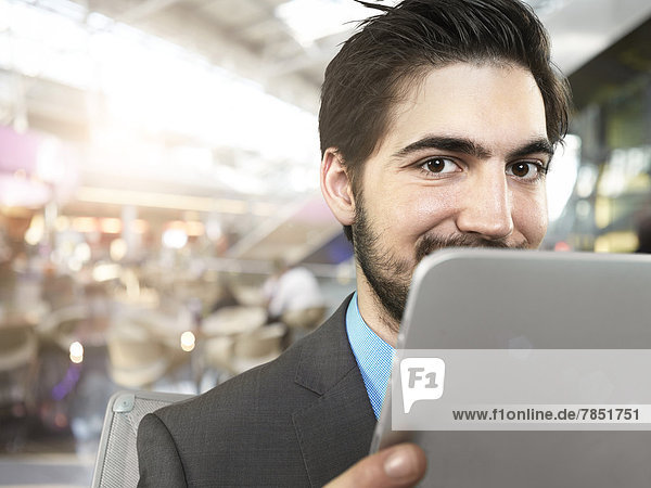 Portrait of young businessman using digital tablet  smiling