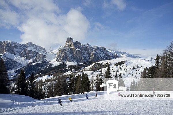 Skiers at the Alta Badia ski resort with Sassongher Mountain in the distance  Dolomites  South Tyrol  Italy  Europe