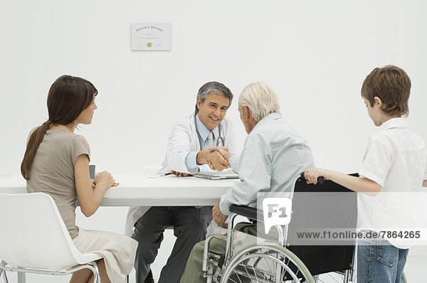 Arzt im Gespräch mit dem älteren Patienten und seiner Familie