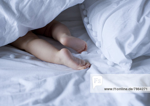 Babys nackte Füße unter der Bettdecke  abgeschnitten