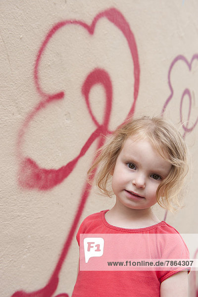 Kleines Mädchen an der Wand mit Blumengraffiti  Portrait