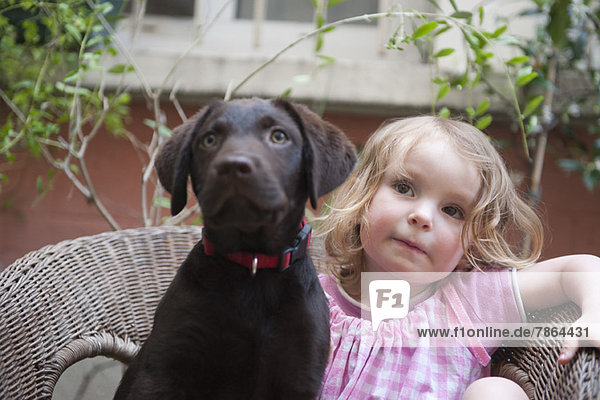 Little girl sitting by pet dog