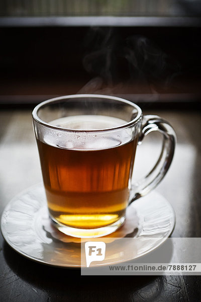 Glas mit heißem Tee auf Untertasse