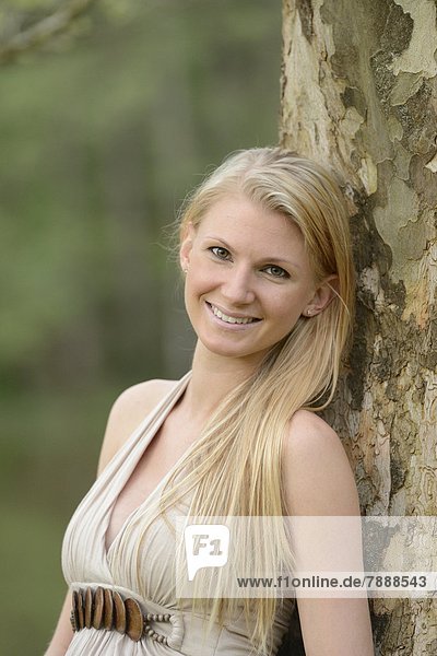 Young pregnant woman leaning on a tree trunk  portrait
