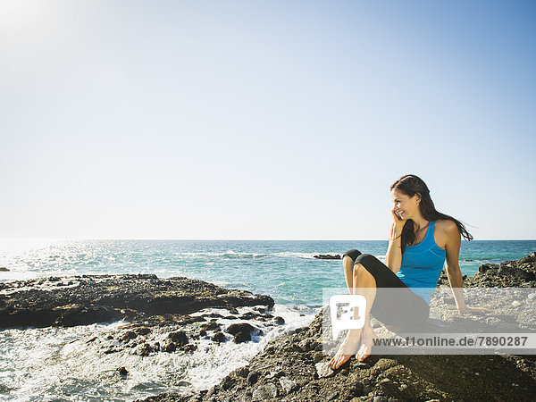Mixed race woman smiling on rocky beach