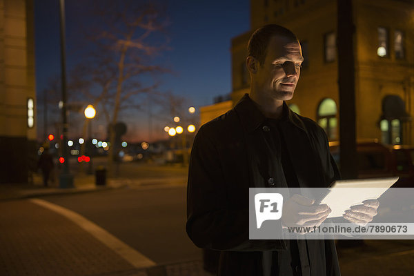 Caucasian man using tablet computer on city street