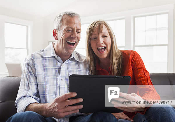 Caucasian couple using tablet computer on sofa