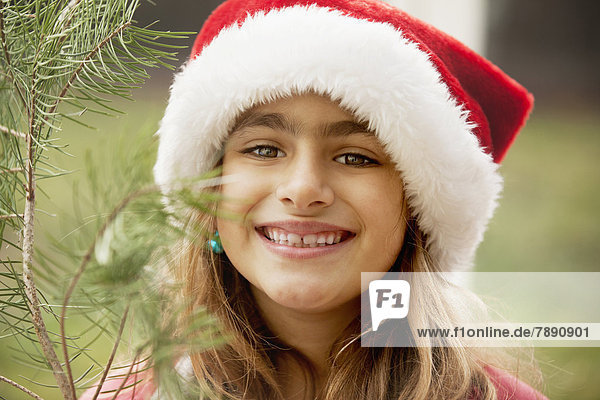 Mixed race girl smiling in Santa hat