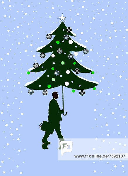Snow falling around businessman with Christmas tree umbrella