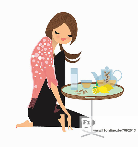 Frau genießt Ingwer- und Zitronentee an einem kleinen Tisch
