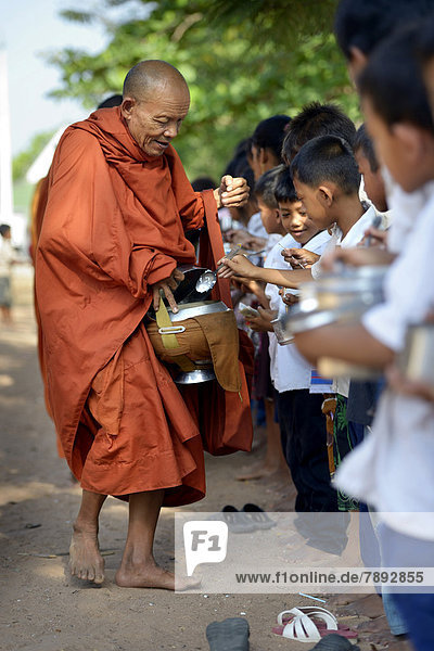 Children donating food and money to a Buddhist monk  traditional ceremony as part of the celebration of the Cambodian New Year