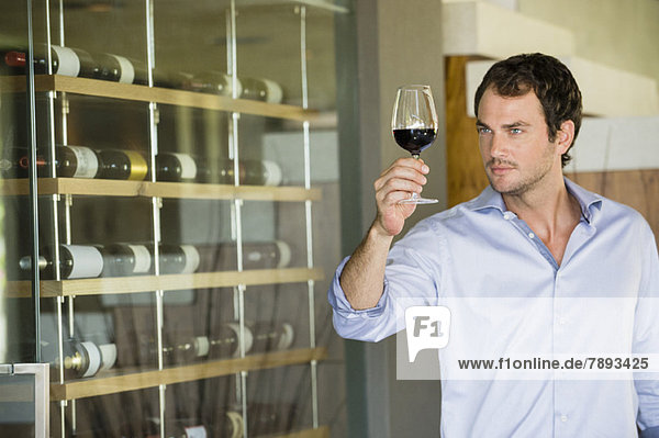 Man looking at red wine in a wineglass