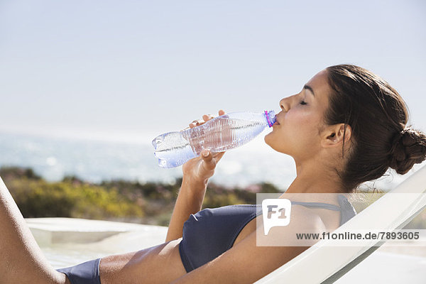 Schöne Frau trinkt Wasser am Strand