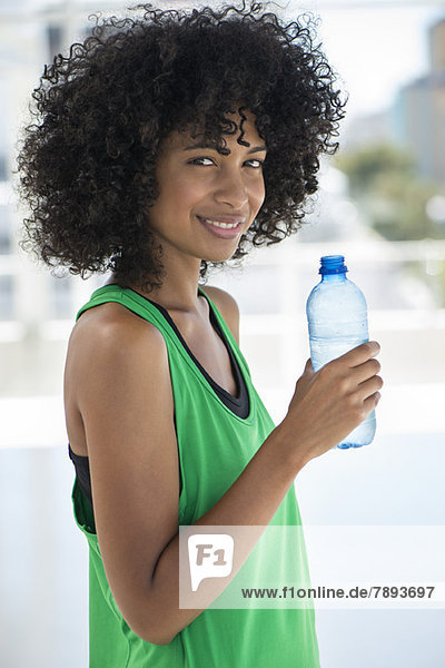 Porträt einer Frau  die eine Wasserflasche hält und lächelt