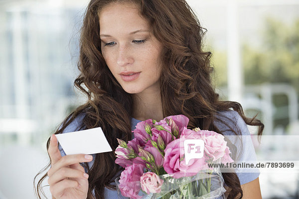 Woman reading a card with bouquet of flowers
