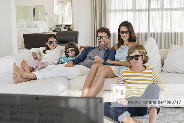 Family watching television at home while wearing 3D glasses