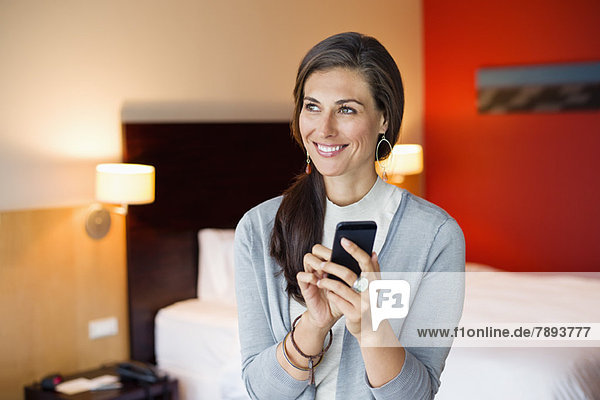 Frau mit Handy im Hotelzimmer