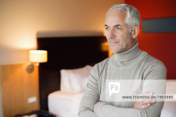 Man with arms crossed in a hotel room