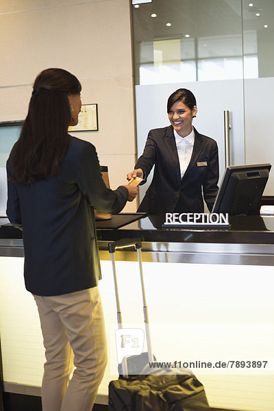 Geschäftsfrau beim Bezahlen mit Kreditkarte an der Hotelrezeption