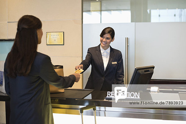 Businesswoman paying with a credit card at the hotel reception counter