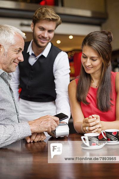 Waiter showing credit card reader to a couple on a table in a restaurant