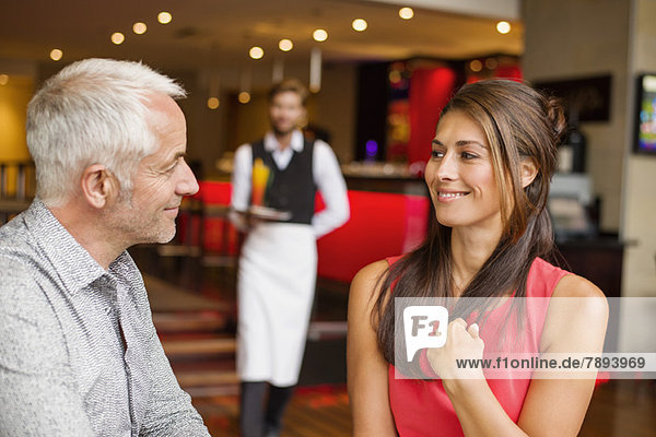 Couple smiling in a restaurant with waiter in the background