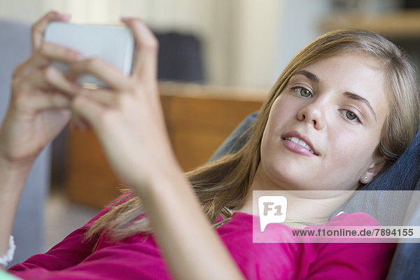 Porträt eines Mädchens  das ein Handy benutzt und lächelt