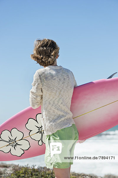Boy holding a surfboard on the beach
