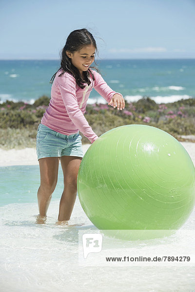 Mädchen beim Spielen mit einem Fitnessball am Strand
