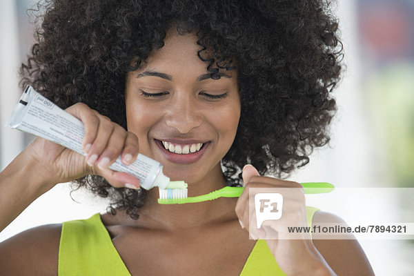 Frau beim Auspressen von Zahnpasta auf einer Zahnbürste