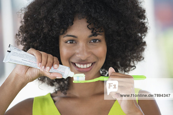 Frau beim Auspressen von Zahnpasta auf einer Zahnbürste