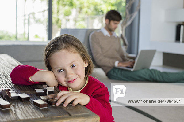 Porträt eines lächelnden Mädchens mit ihrem Vater mit einem Laptop im Hintergrund