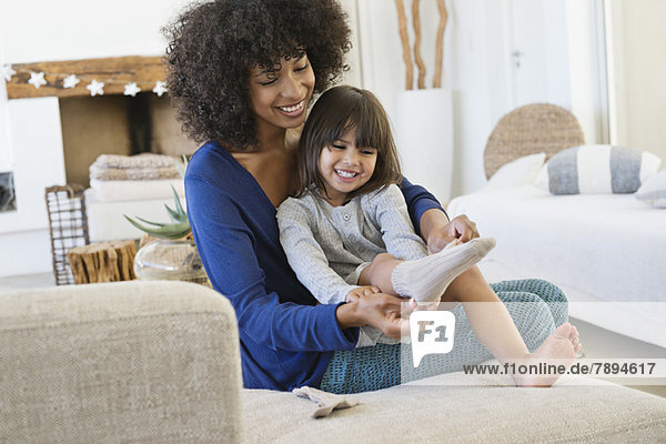 Woman putting on socks to her daughter and smiling