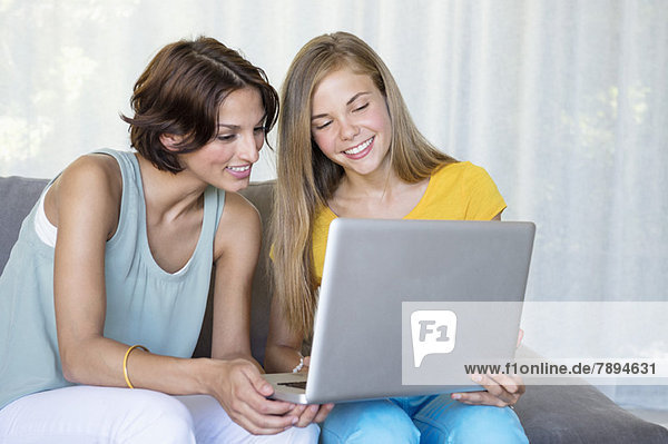 Lächelnde Mutter und Tochter beim Betrachten eines Laptops