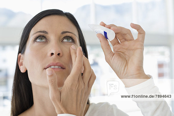 Woman applying eye drops into eye
