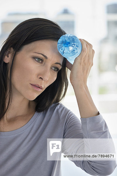 Woman holding a water bottle on her forehead