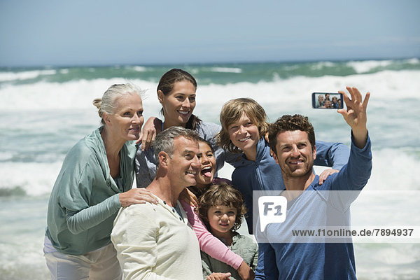 Happy multi-generation family taking a self portrait with a cell phone on the beach