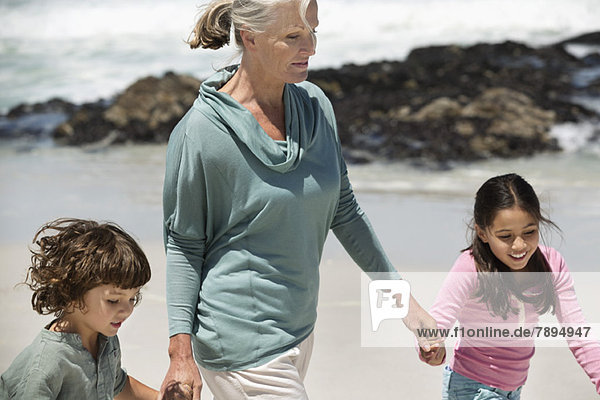 Woman playing with her grandchildren on the beach