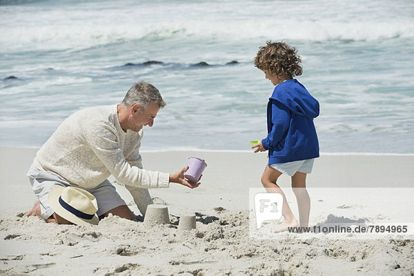 Junge spielt mit seinem Großvater am Strand