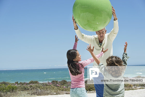 Mann spielt mit seinen Enkeln am Strand
