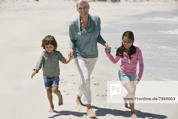 Frau spielt mit ihren Enkelkindern am Strand