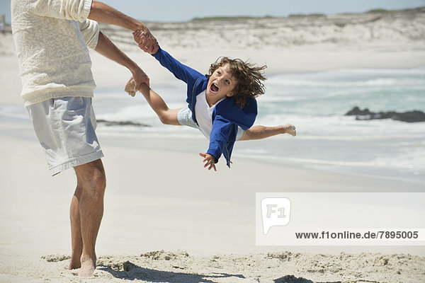 Mann spielt mit seinem Enkel am Strand