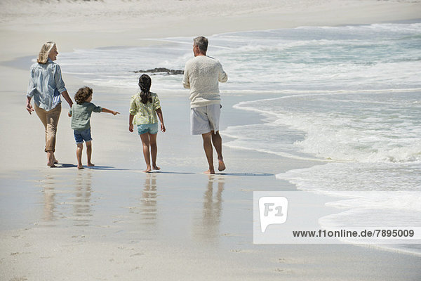 Children walking with their grandparents on the beach