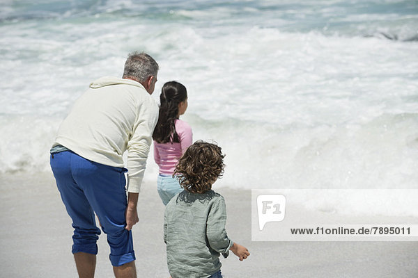 Kinder mit ihrem Großvater beim Surfen am Strand