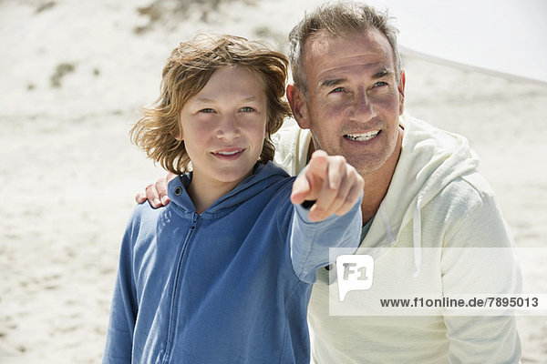 Junge zeigt mit seinem Großvater auf den Strand